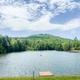 Wide view of the campground’s lake with dock and tree-lined shore — useful scenic overview of on-site water recreation shown in site imagery.