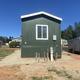 Rear/exterior view of a mobile home with adjacent RV — demonstrates mixed mobile-home and RV presence on-site (used in Lot 52 listing context).