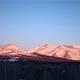 Distant mountains lit by sunrise/sunset — photographic exterior view used on the lodging page that highlights the surrounding mountain scenery visible from the property.