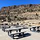 A view of the Taos Junction group site area with picnic tables, concrete pad, fire pan, and trash receptacles. 