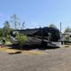 Large motorhome parked on a gravel/leveled pad with hookups visible — shows an RV pitch and surface type useful for guests (gallery page).