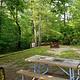 Horse corrals sit near green canopy of forest behind the gravel tent pad of a campsite.
