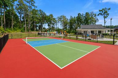 Recreation court (pickleball/tennis) with clubhouse and playground visible beyond — useful to show on-site activities and open recreation space.