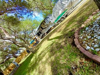 Shaded paved RV site with parked RV, boat trailer and mature trees — illustrates site size, paved pad and landscaping (matches homepage/site descriptions of large, paved sites).