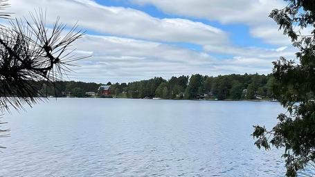 Scenic lake view across the water with shoreline trees and nearby buildings visible — directly relevant to the campground’s waterfront on the Our Water page.