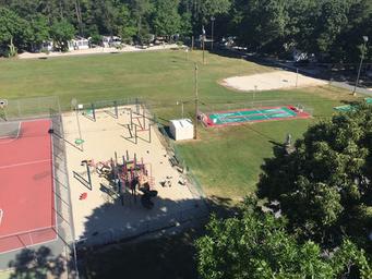 Aerial/upper-level view of recreation fields, playground and courts with surrounding campsites — provides an overview of grounds layout and multiple amenities.
