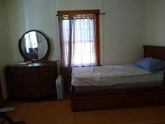 A bed next to a dresser and window.