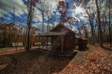 Exterior shot of a single cabin on wooded grounds with surrounding trails and site features; good for illustrating the cabin setting and landscape on the property.