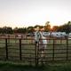Portrait-style shot of a white horse in a round pen with paddocks and RVs visible behind at sunset — highlights equine facilities and campsite proximity (present on the site home/gallery images).