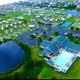 High-resolution aerial overview showing the resort layout: clubhouse with large pool, two ponds, RV loops, tennis/pickleball and mini-golf — matches site header and identifies property features and overall scale.