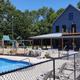 Exterior view of the campground pool and adjacent multi-story building and playground — clearly shows on-site pool facility. Image appears on the home page (Slide-Pool) of the property website.