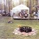 Close campsite scene with fire ring, canopy, picnic tables and surrounding woods illustrating a private campsite setup; sourced from the campground’s photo gallery (Whitetail Ridge Campground Photos).