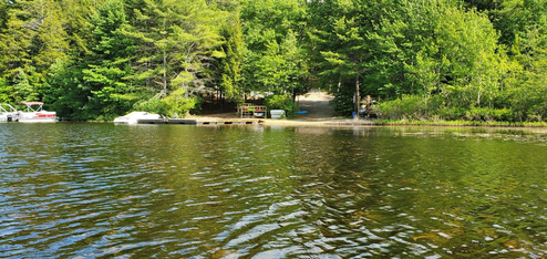 Wide waterfront panorama showing boats, dock and sandy shore — useful overview of the campground shoreline and boat access (background/header image on the site).