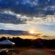 Sunset scene across the campground showing an RV, canopy and picnic table with natural vegetation and horizon — attractive scenic shot of on-site campsites (from the Welcome page).