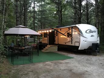 RV parked at a site with outdoor seating and canopy—good representation of RV accommodations and site setup; from the property’s photo gallery.