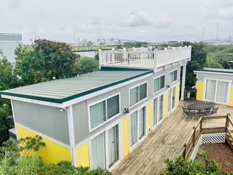 Elevated/oblique view of multi-unit villas with rooftop deck and adjacent boardwalk — provides overall site layout and building arrangement; from the property photo gallery (image-12-new-1.jpg).