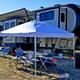 Close view of a pull-through RV campsite with awning/canopy, chairs and truck — clear depiction of a typical occupied site and amenities available to guests (from the Welcome/Rates gallery images).