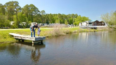 Fishing dock and waterfront view showing cabins and RVs across the lake — appears on the property’s community page and highlights lake access and on-site cabins.