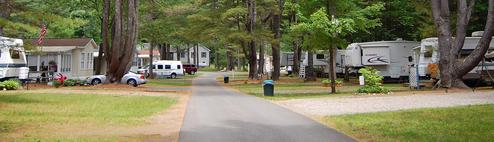 Panoramic view down a paved park road lined with RV sites and hookups — useful overview of typical RV pitches and site spacing. Source page: Park map header / park map context.