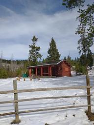 High Rye Cabin, view from parking lot,  Red Cabin with snow on the ground surrounded by green trees
