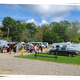 Clear daytime photo of RVs and vehicles lined up on grassy sites with guests — shows the campground's RV pitches and overall site layout; sourced from the main site photo gallery/activity area.