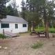 A cabin next to picnic tables and a fire ring.