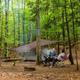 Tent campsite in a wooded setting with gear and a firepit — useful campsite lifestyle image from the campground's 'ways to stay' photos.