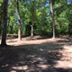 Ground-level photo of a tent/campsite area with picnic table and surrounding trees—useful for showing typical tent/campsite layout and forested scenery on the campground grounds.