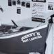 A vintage black and white photo of two people standing beside a boat labeled 'Johnny's Boat Landing'.
