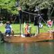 On-water activity (children in a homemade boat) with campground shoreline and docks visible — illustrates recreational use of the property’s lake (homepage slider).
