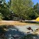 Tent campsite with fire ring, picnic table and cleared pad — close, helpful view of a tent pitch and amenities present on the property.