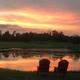 Outdoor sunset view across a pond with two Adirondack chairs — shows the venue's lakeside scenery and tranquil grounds (image appears on the property's homepage).