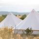 Close-up of bell tent peaks set in the landscape with distant hills — useful as an iconic image of the glamping tents and surrounding scenery at the property (sourced from the site).