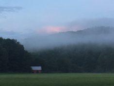 Wide scenic view with mist/fog over open fields and a distant barn — gallery image that captures campground surroundings and atmosphere.