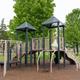 Playground equipment in a grassy area with trees and RVs visible in background — good representation of family-friendly on-site facilities.