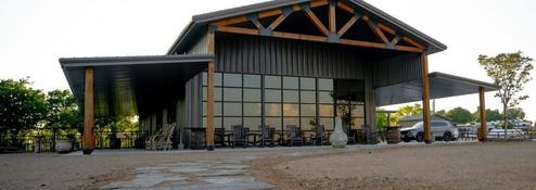 Frontal ground-level shot of the clubhouse/building with covered porch and seating; labeled in site’s amenities content as clubhouse groundshot (page: /amenities).