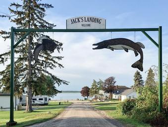 Entrance sign arch with 'Jack's Landing' and view straight down to the lodge and lake — clearly identifies the property entrance and grounds (from site background/entrance image).
