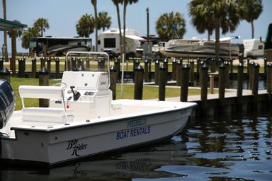 Clear waterfront shot showing a rental boat in the marina with RVs, docks and grassy park area in the background — supports marina and RV slip amenities (from the site's Boat Rentals context).