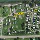 Aerial overhead overview of the campground showing site layout, road, lakeshore and labeled pitch/area markers — useful as an overall property map/overview.