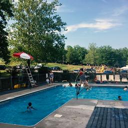 Swimming pool with lifeguard chair and loungers, guests in pool area — documents the campground’s pool amenity (from the Amenities page).