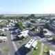 Aerial view showing the overall RV park layout, roads, parked RVs and the pool area; matches gallery page context and clearly depicts the property grounds.