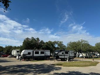A row of rvs parked in a lot with trees in the background.