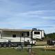 Ground-level photo showing an RV and tow vehicle on a full-hookup site with picnic table and open lot — good campsite detail; comes from the McAlpin page hero image.