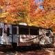 RV in a wooded campsite during fall foliage — a distinct seasonal view of campsite RV accommodations referenced in the property's 'ways to stay' gallery.