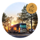 Framed photograph of an RV parked at a gravel/stone pad with surrounding trees and site amenities — shows an actual RV site available at the resort.