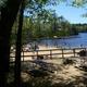 Sandy beach with picnic tables, people and a dock on a lake — depicts a campsite beach/amenity area that would be relevant for the campground gallery (sourced from the same NH campground page).