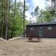 Exterior of a standalone rental cabin on cleared site with picnic table and surrounding trees — useful to show accommodation options (from the ‘Rental Cabins’ page).