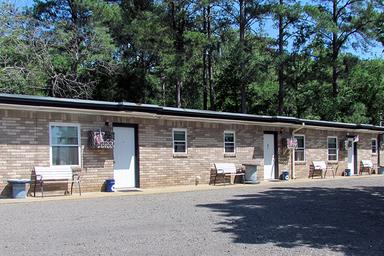 Exterior of the motel building (row of rooms) showing guest entrances and parking — useful to represent the motel accommodation on the property (from the site).