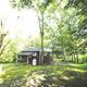 Cabin exterior set in trees, showing accommodation type available on the property. Source page: cabin page image.