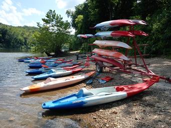 Kayaks and boats stacked along the riverbank showing equipment rental/launch area — useful facility image and matches floating page context on the site.